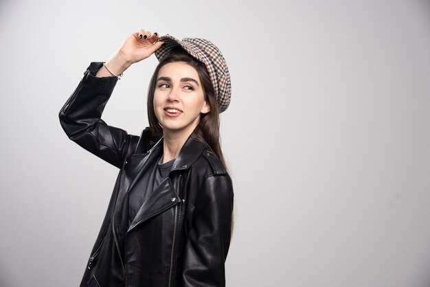 Photo of a woman posing in black leather jacket and cap.