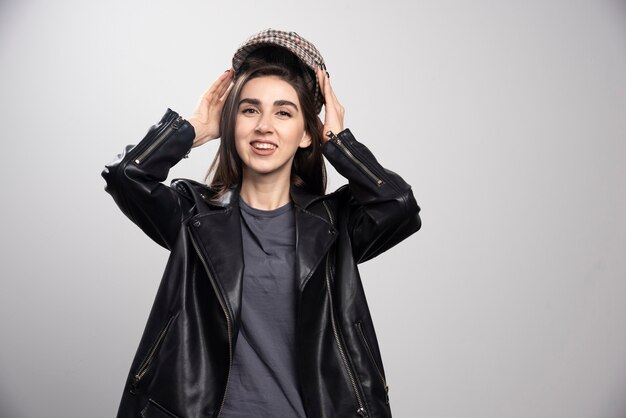 Photo of a woman posing in black leather jacket and cap.