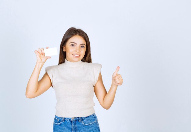 Photo of young beautiful woman model holding a card and showing a thumb up.