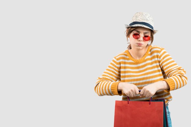 Photo of young brunette woman in sunglasses holding shopping bags. High quality photo