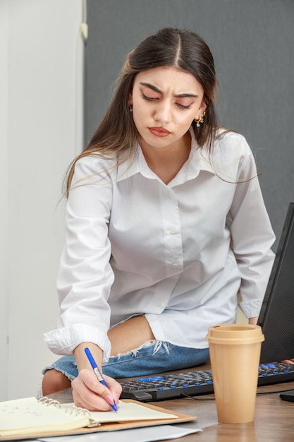 Photo of young businesswoman taking notes at the office High quality photo