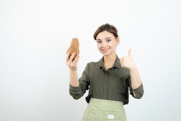 Photo of young girl holding hairy coconut over white. High quality photo