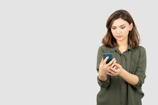 Photo of young girl with cellphone standing and checking her messages