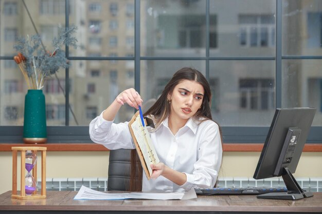 Photo of young lady holding notebook and showing to the camera