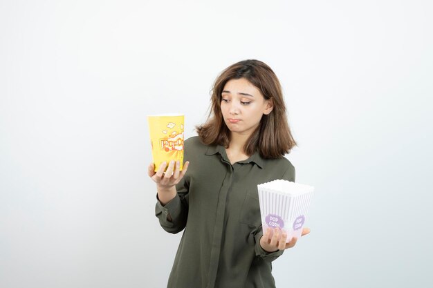 Photo of young woman in casual outfit holding popcorn. High quality photo