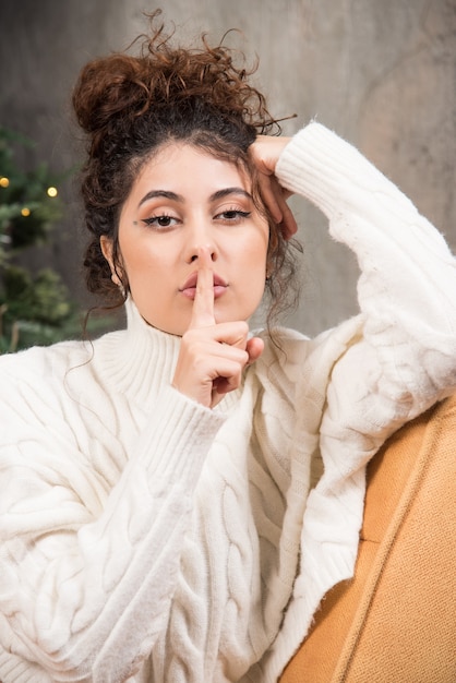 Photo of young woman sitting in comfy chair near Christmas tree