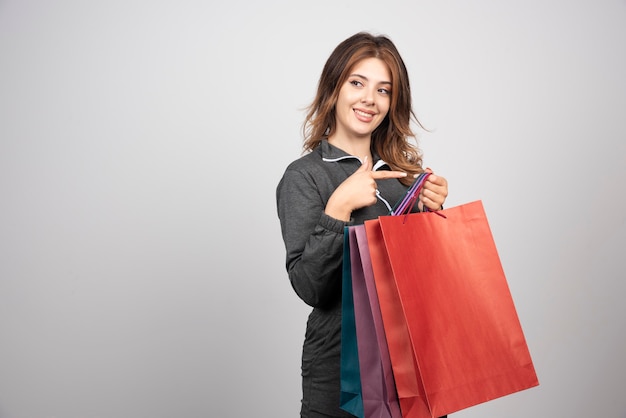 Photo of young woman with shopping bags and waving hand.