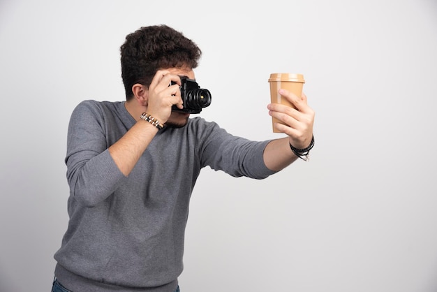 Free photo photograph holding a plastic coffee cup to take photos.