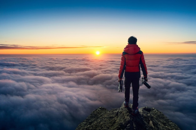 Free Photo photographer hand holding camera and standing on viewpoint over clouds. panorama viewpoint at sunrise.