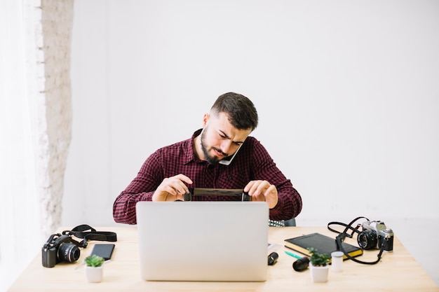 Photographer using laptop while talking by mobile phone