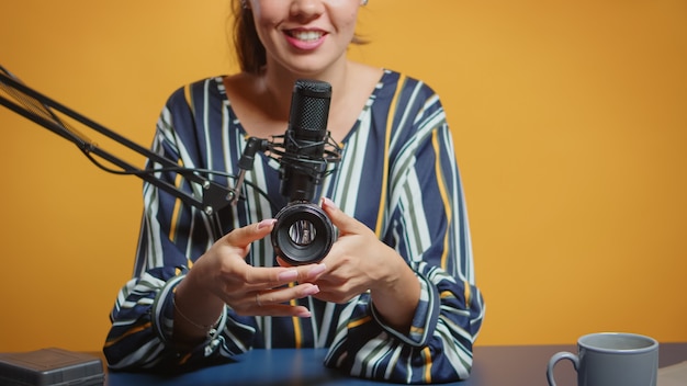 Free Photo photography expert talking about camera lens in her weekly podcast for subscribers. content creator new media star influencer on social media talking video photo equipment for online internet web show