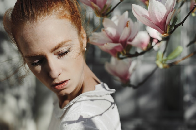 Free photo photoshoot of redhead woman near a magnolia  flowers