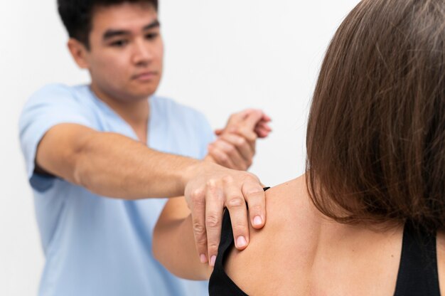 Physiotherapist doing shoulder exercises with female patient