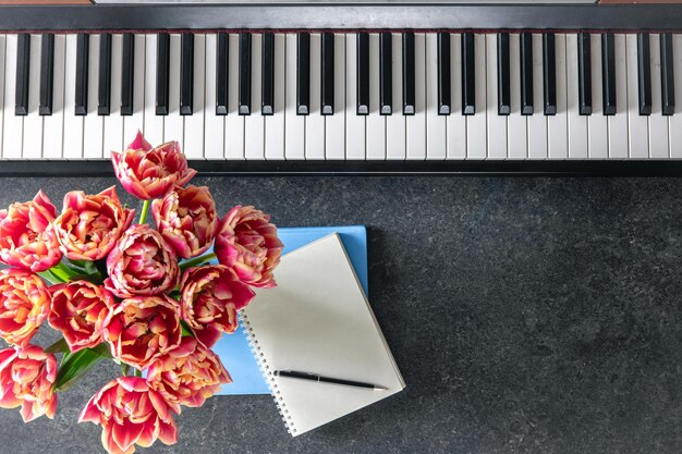 Piano bouquet of flowers and notepads on a dark background top view