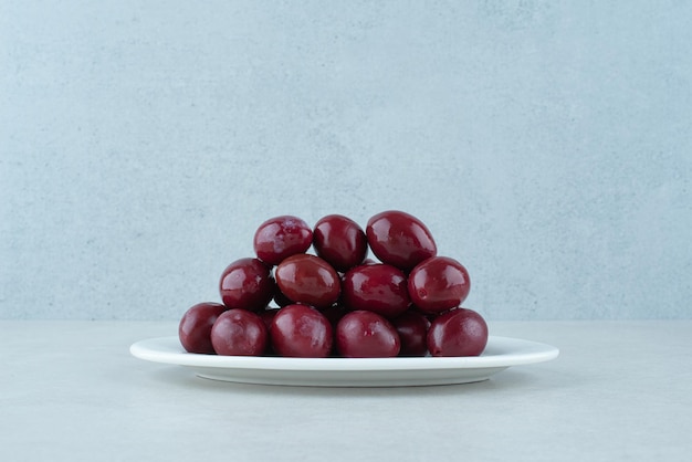 Pickled cornel cherries on white plate.