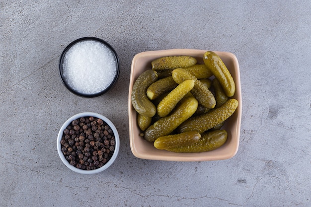 Pickled cucumbers in bowls placed on stone table.