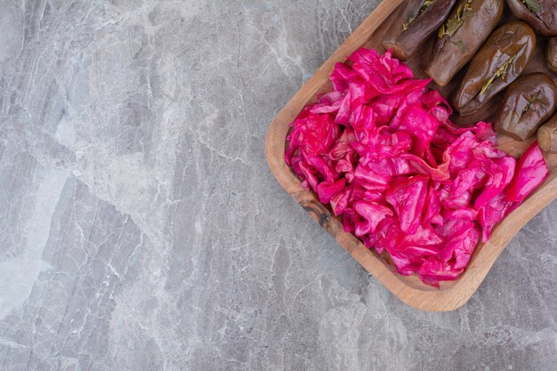 Pickled eggplants and red cabbage on wooden board.