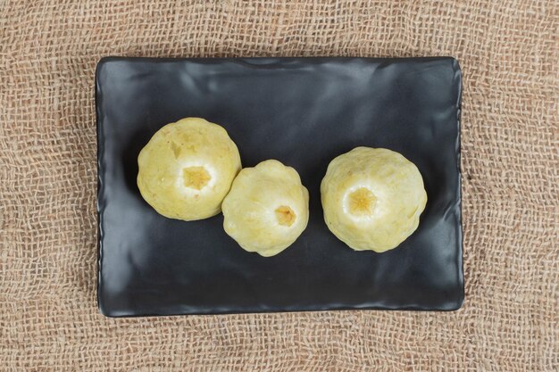 Pickled fruits on black plate with burlap