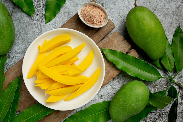 Pickled mango on dark wooden surface