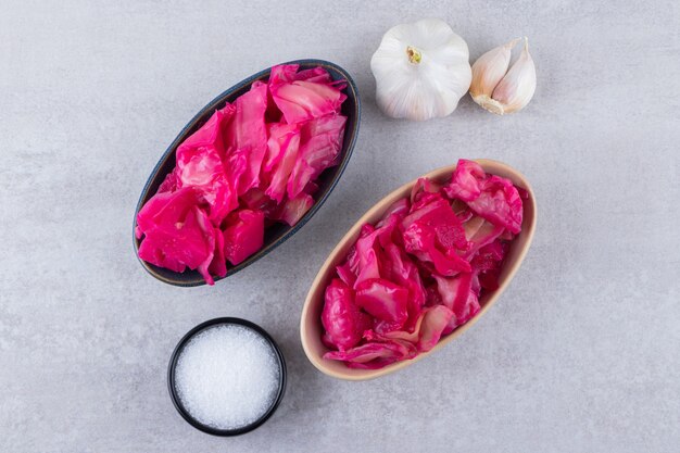 Pickled red cabbage with fresh garlic and pepper corns placed on stone table .