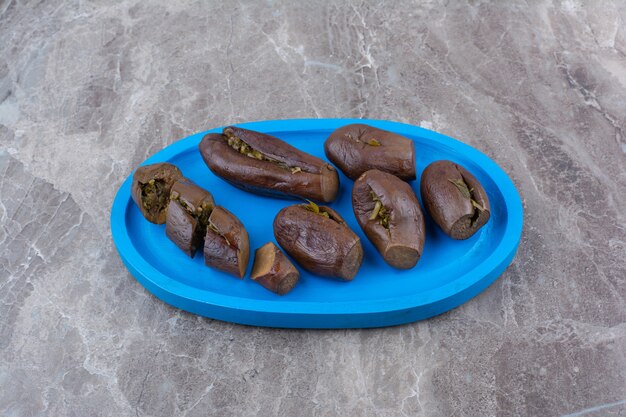 Pickled stuffed eggplants on blue plate.