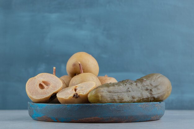 Pickles cucumber and apples on wooden plate    