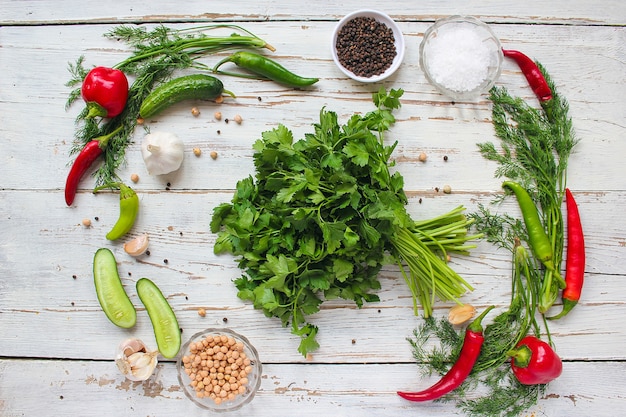 Free photo pickles on white wooden table with green and red and chili peppers, fennel, salt, black peppercorns, garlic, pea, close up, healthy concept, top view, flat lay