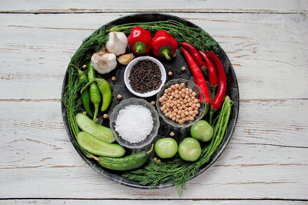 Pickles on white wooden table with green and red and chili peppers, fennel, salt, black peppercorns, garlic, pea, close up, healthy concept, top view, flat lay