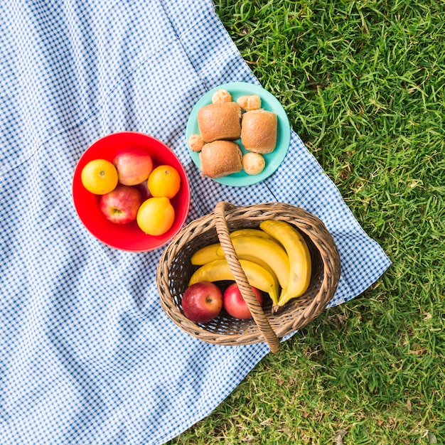 Free Photo picnic basket with fruits and bread on check blanket over green grass