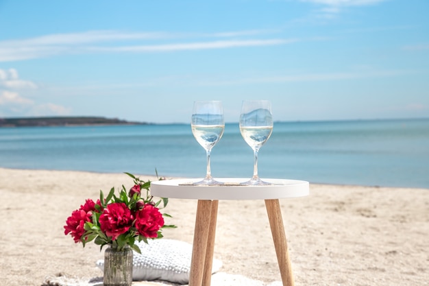 Picnic by the sea with flowers and a glass of champagne. The concept of a holiday.