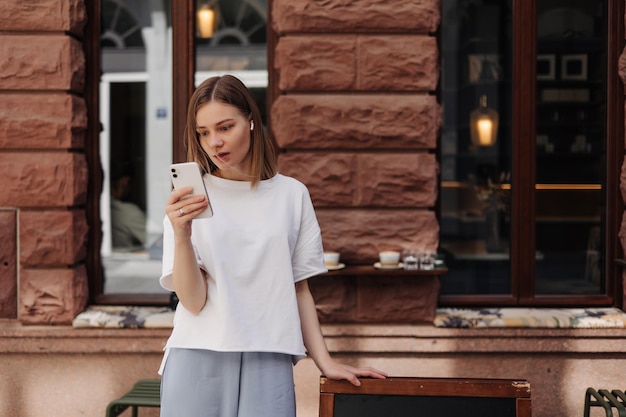 Picture of attractive woman holding phone in white tshirt