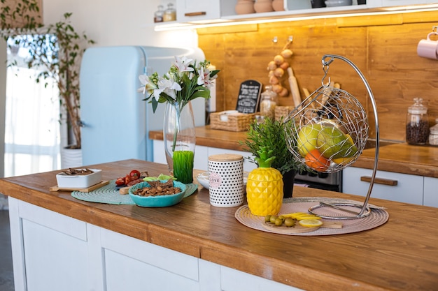 Picture of the big bright kitchen with white and brown cupboards with yellow pineapple tea kettle, white pepper mill and metal hanging with fruits