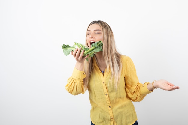 Free Photo picture of a cute pretty woman model standing and trying to eat cauliflower.