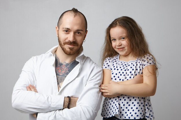 Picture of fashionable bearded young Caucasian father with stylish haircut and tattoo