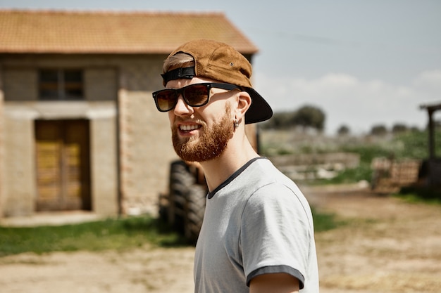 Free photo picture of handsome cheerful young farmer with thick beard spending weekend in countryside