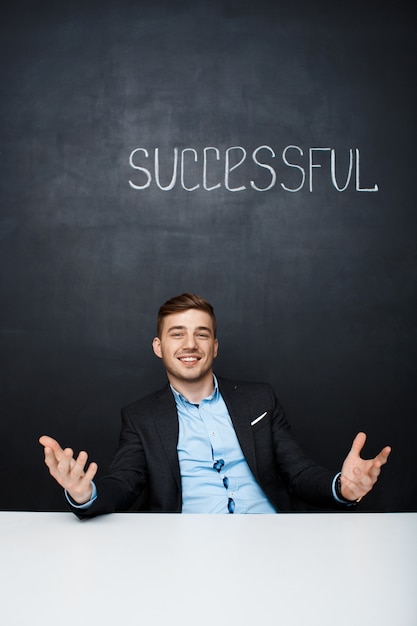 Free photo picture of a happy man over black board with text successful