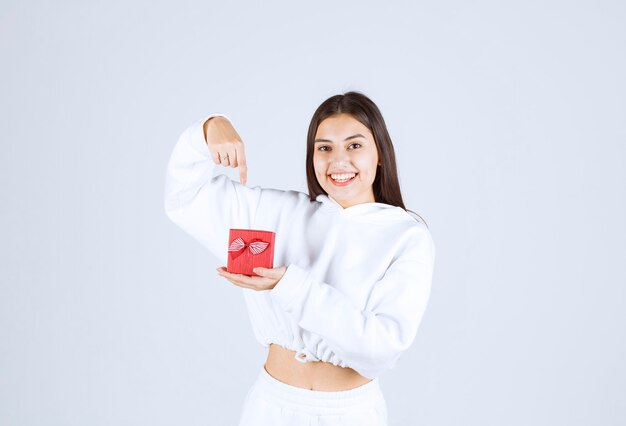 Picture of a pretty young girl model pointing at a gift box.