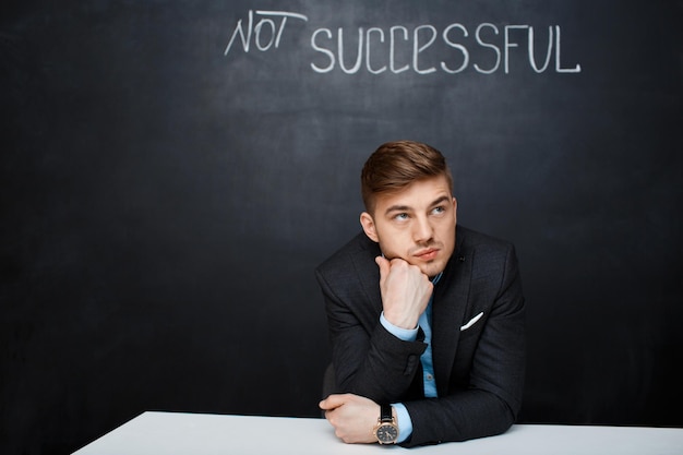 Picture of sad concetrated man over black board with text