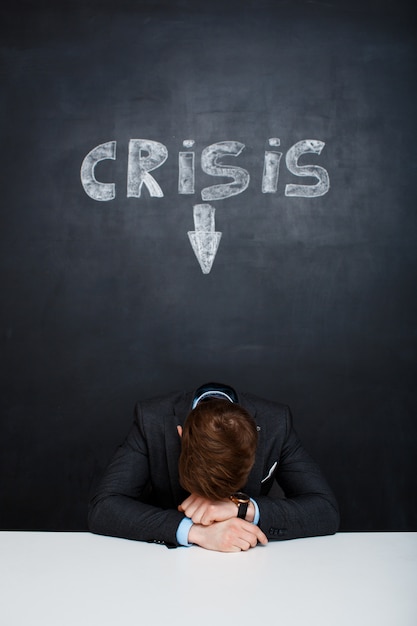 Free photo picture of tired man over blackboard with crisis inscription