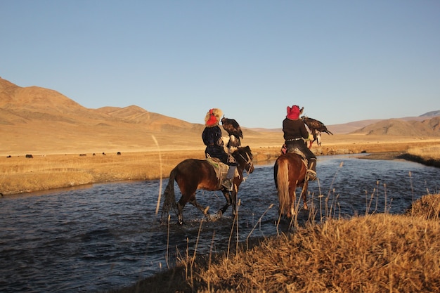 Free Photo picture of two horseriders in a river surrounded by a deserted valley with hills