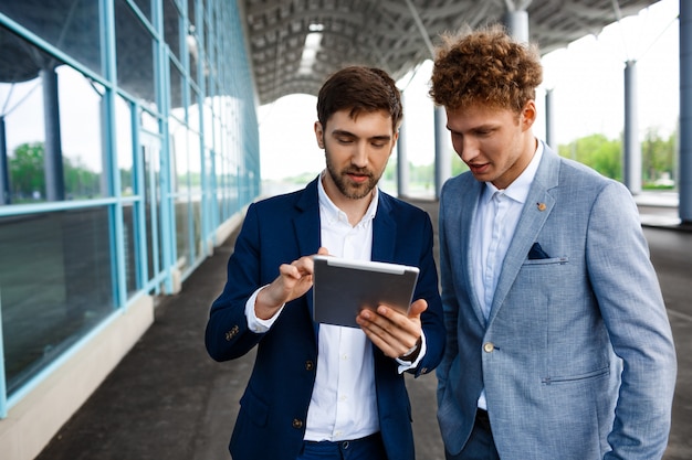 Free photo picture of  two young businessmen talking on terminal  and holding tablet