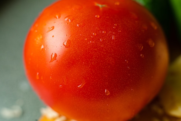 Free photo picture with focus on washed red tomato lies on the table with drops of water on it