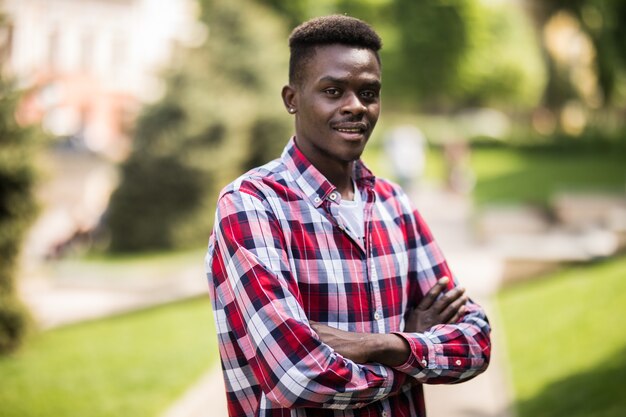 Picture of young african man walking on the street standing with arms crossed.