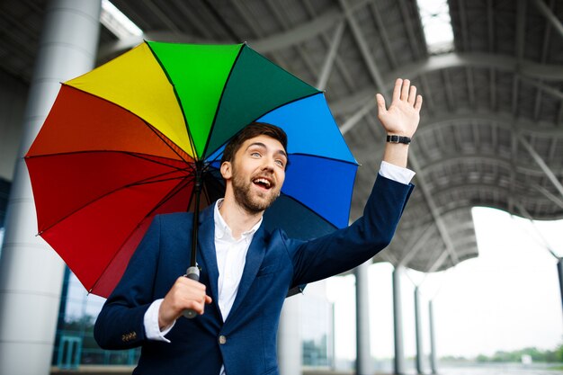 Picture of  young businessman holding motley umbrella showing high-five