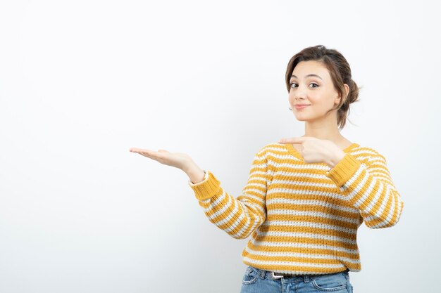 Picture of a young pretty woman model pointing at opened palm . 