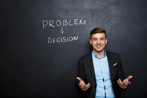 Picture of young suited man near text vote over blackboard