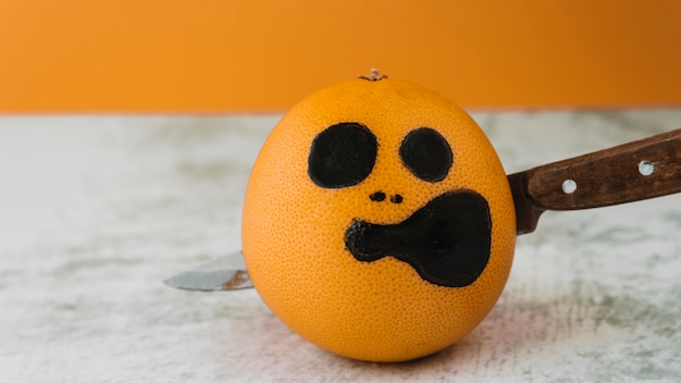 Free photo pictured face on fruit with pierce knife inside