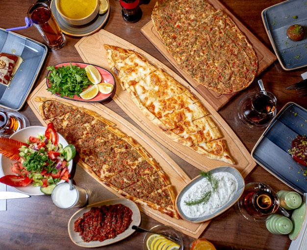 Pide and lahmajun served with salad, greens and lemon, lentil soup and ayran