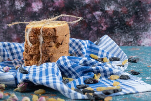 Pie slices with dry grapes on blue checked towel.