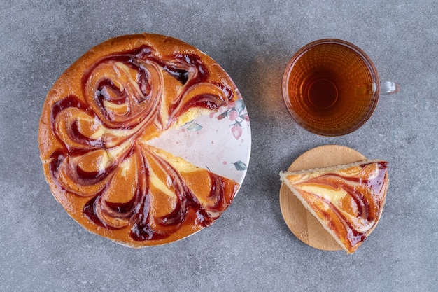 Pie with berry and cup of tea on marble surface